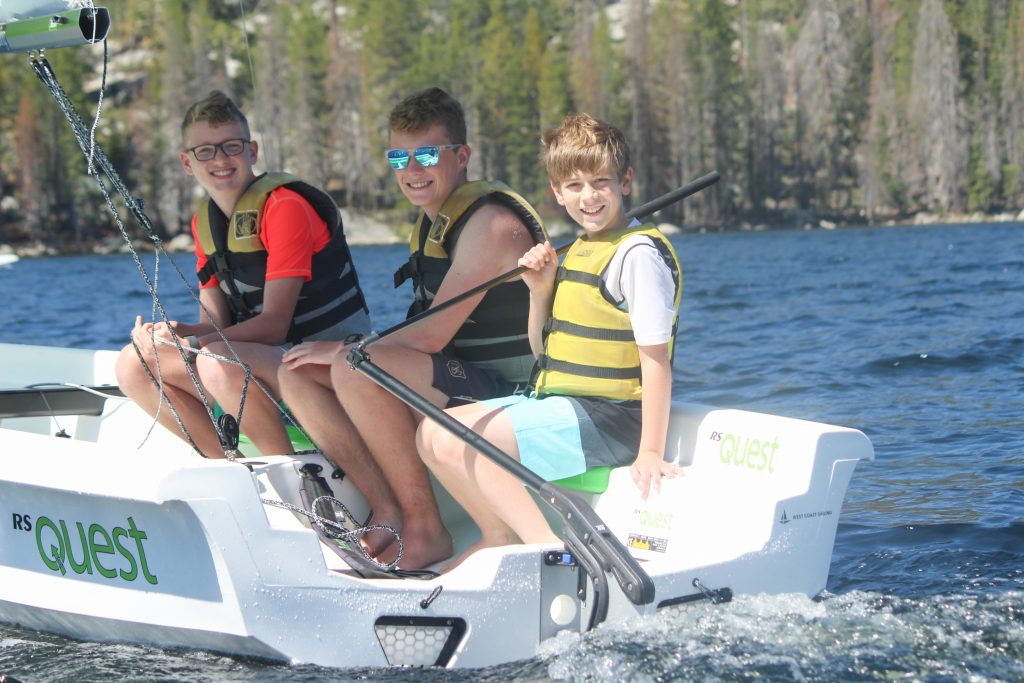 Three boys sail at a summer camp on Huntington Lake in California, Gold Arrow Camp